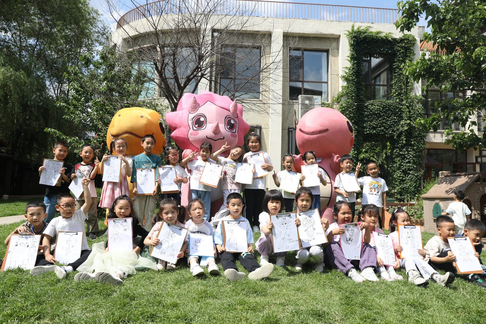 Children holding dinosaur drawings during a Three Little Dinosaurs activity